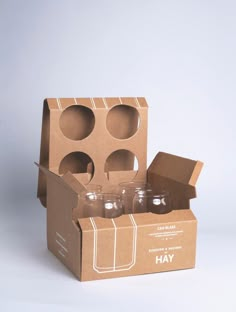 an open cardboard box with four empty glass jars in the bottom and one on the inside