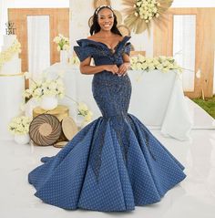 a woman in a blue dress standing next to a table with flowers and cake on it