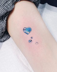 a small heart tattoo on the left inner arm and lower arm, with water droplets coming out of it