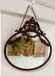 a mirror hanging from the side of a wall with flowers and pine cones on it