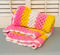 a crocheted blanket sitting on top of a table next to a white chair