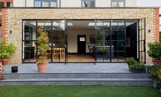 an open patio area with potted plants on the side and glass doors to another room