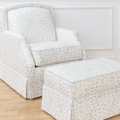 an upholstered chair and footstool in a living room