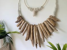 a necklace made out of driftwood is hanging on the wall next to a potted plant