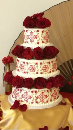 a three tiered wedding cake with red roses on it