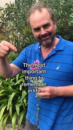 a man in blue shirt holding up a plant with words on the front and back