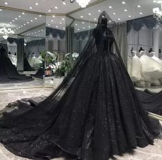 a black ball gown is on display in front of a mirror with lights hanging from the ceiling