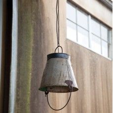 an old metal bell hanging from the side of a building with a chain attached to it