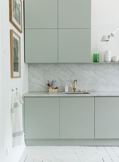 a kitchen with marble counter tops and gray cabinets in the corner, along with pictures on the wall