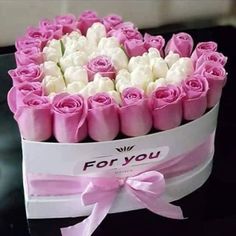 pink and white roses are in a box on a black table with the words for you