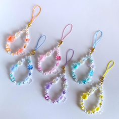 four bracelets with beads and charms hanging from the side on a white surface,