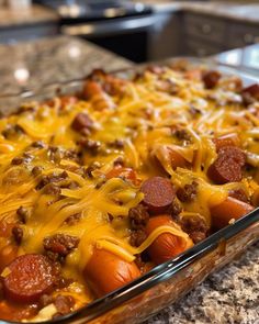 a glass casserole dish filled with hot dogs and cheesy toppings