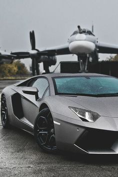 a silver sports car parked in front of an airplane