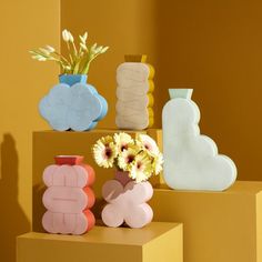 three vases with flowers are sitting on top of each other in front of a yellow wall