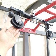 a hand is holding the pulley bars on a gym equipment set up in front of a window