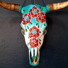 a cow skull with flowers painted on it's face and horns hanging from the wall