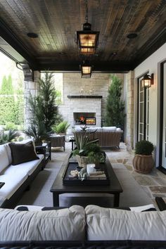 an outdoor living area with couches, tables and lamps on the ceiling is decorated in black and white