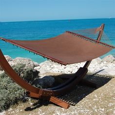 a hammock sitting on top of a rock next to the ocean