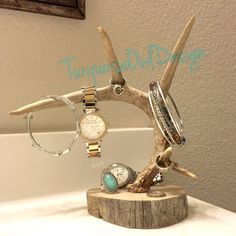 an antler branch with rings and bracelets on it sitting on top of a table