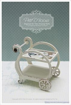 a miniature baby's carriage made out of wood and white paint with an ornate frame