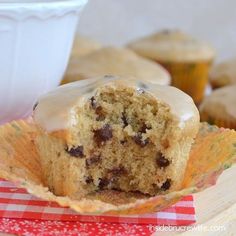 a cupcake with frosting and chocolate chips in it sitting on a napkin next to some muffins