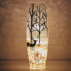 a glass vase with an image of a deer in the woods on it's side