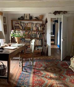 the room is full of books and furniture, including a desk with two lamps on it