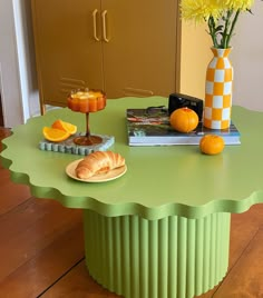 a green table topped with oranges and pastries