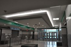 an empty lobby with tables and stools in it's center area, next to the entrance