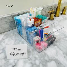 there is a clear plastic container on the sink counter with personal care items in it