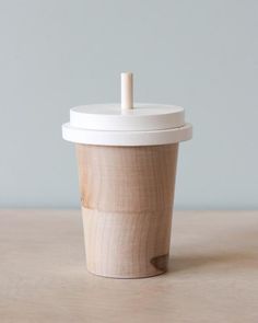 a wooden cup with a white lid sitting on top of a table