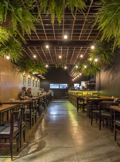 the inside of a restaurant with tables, chairs and plants hanging from the ceiling above