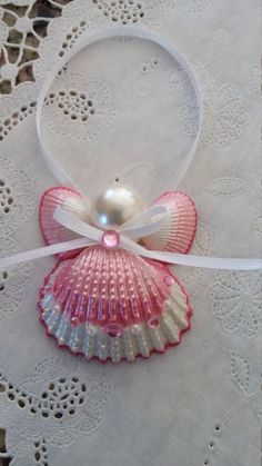 a pink and white shell with a pearl in it's center on a lace doily