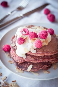 a stack of pancakes topped with whipped cream and raspberries