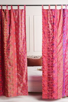 the curtains are open to show pink and purple patterns on them, with a bed in the background