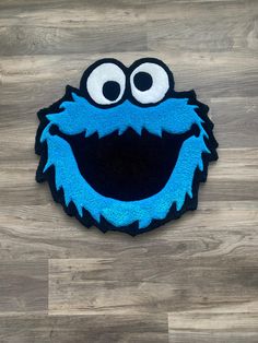 the cookie monster rug has eyes and is on top of a wooden floor with wood planks