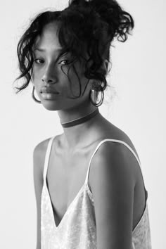 a black and white photo of a woman with curly hair wearing a choker necklace