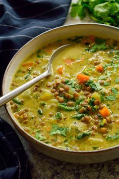 a bowl of soup with carrots, beans and cilantro on the side