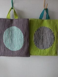 two bags are hanging on the wall and one has a green bag with blue circles