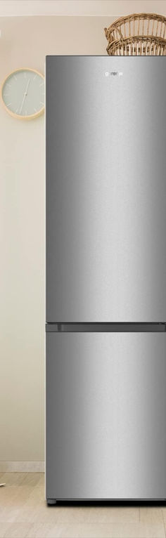 a silver refrigerator freezer sitting on top of a wooden floor next to a clock