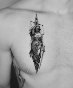 a man with a tattoo on his chest holding a cross and arrow in the shape of a woman's head