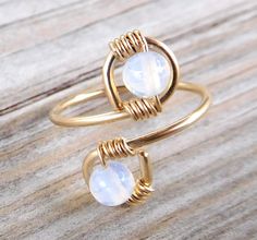 two rings with white stones on them sitting on top of a wooden table next to each other