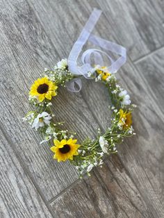 a wreath with sunflowers and baby's breath tied to it on the floor