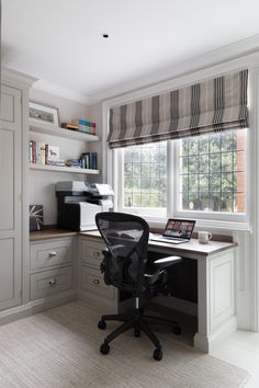 a home office with a desk, chair and printer in the corner by the window