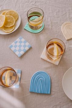 there are some glasses and plates on the table with lemons, water, and paper napkins