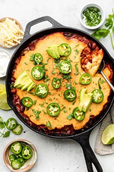 an enchilada dish in a cast iron skillet with sliced jalapenos