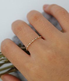 a woman's hand with a gold ring on her finger and the band has five small diamonds