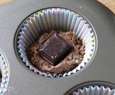 there is a chocolate cupcake in the muffin tins with it's frosting