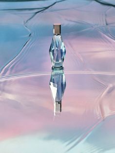 a perfume bottle floating on top of a liquid filled with blue and pink liquid,