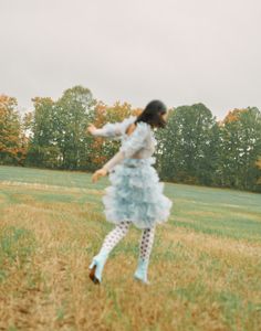 a girl in a blue dress is running through the grass